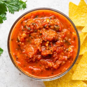 Salsa roja in glass bowl set next to tortilla chips