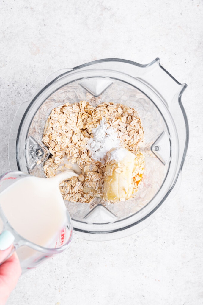 Overhead view of milk being poured into blender with pancake ingredients