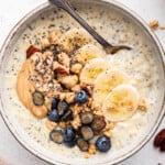 Overhead view of spoon in bowl of creamy protein oatmeal with toppings