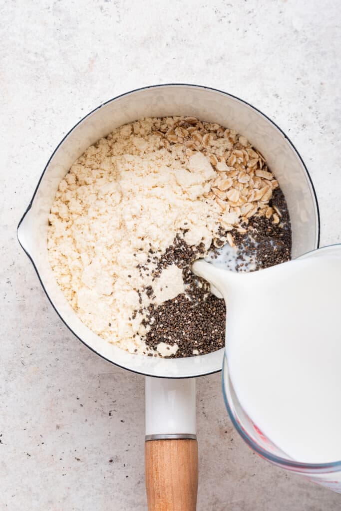 Overhead view of milk being poured into pan with other ingredients for protein oats