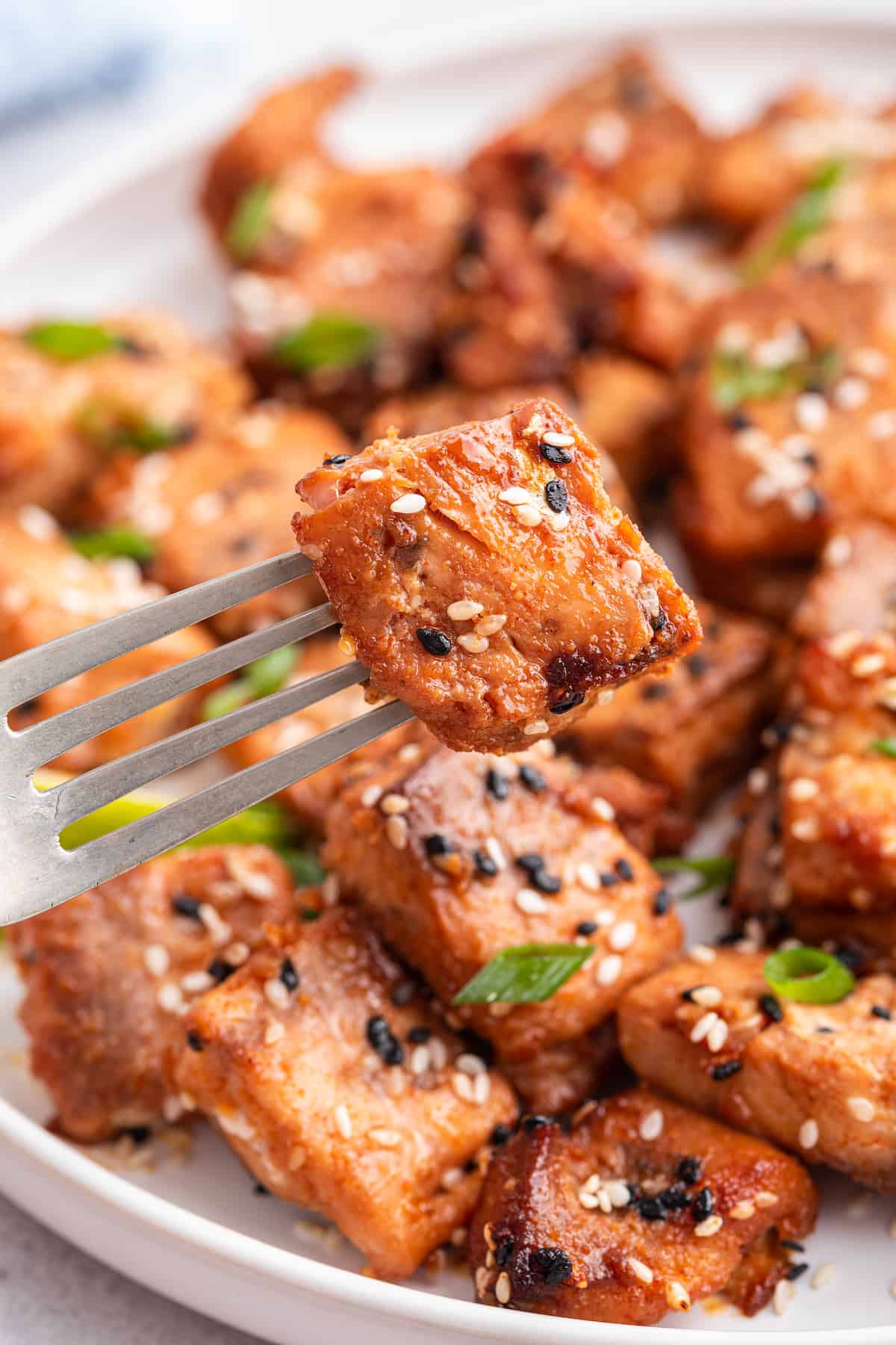 Fork holding air fryer salmon bite over plate