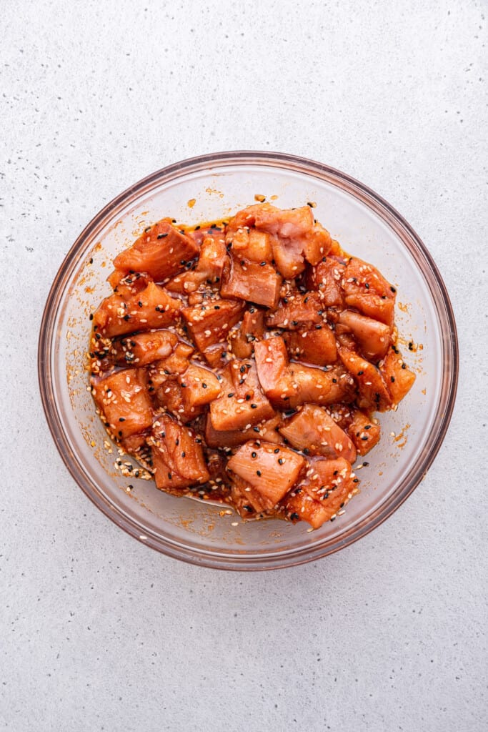 Overhead view of salmon bites in bowl with marinade