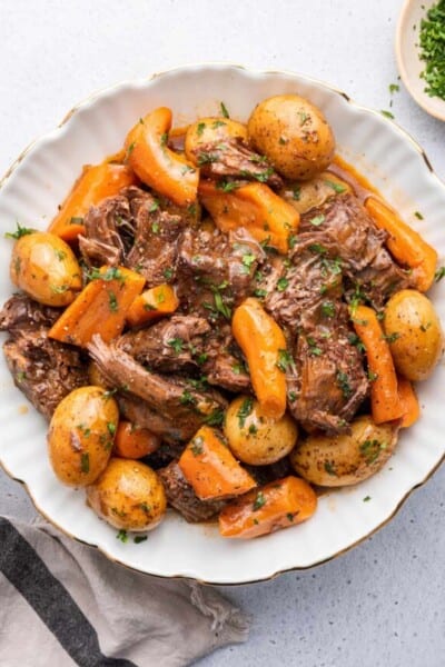 Overhead view of Instant Pot chuck roast with potatoes and carrots on plate with parsley