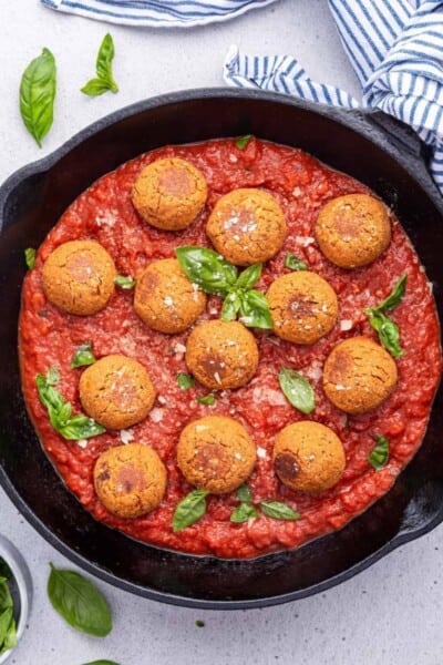 Overhead view of vegan meatballs in cast iron skillet of pasta sauce