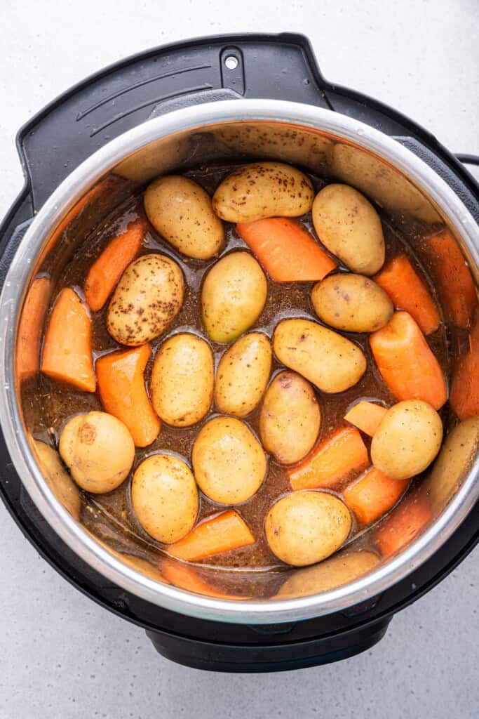 Overhead view of carrots and potatoes in Instant Pot before adding liquid