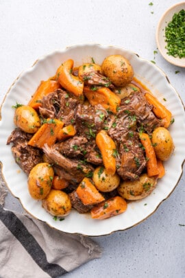 Overhead view of Instant Pot chuck roast with potatoes and carrots on plate with parsley