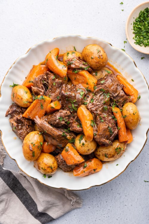 Overhead view of Instant Pot chuck roast with potatoes and carrots on plate with parsley