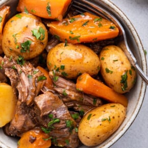 Overhead view of Instant Pot chuck roast with potatoes and carrots in bowl with fork
