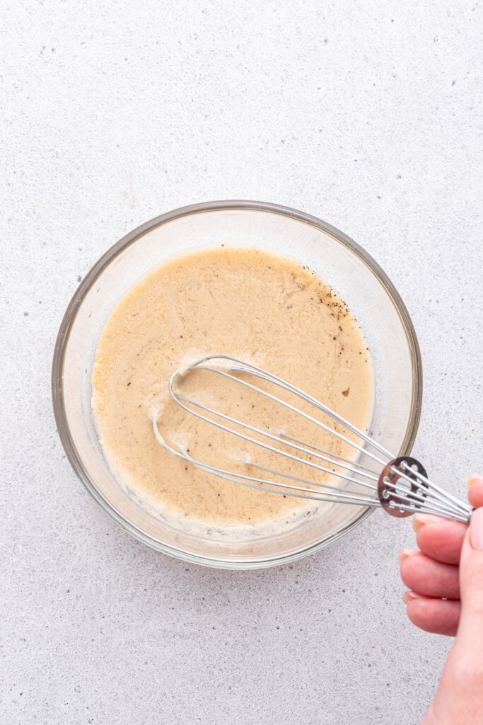 Overhead view of tahini sauce being whisked in bowl