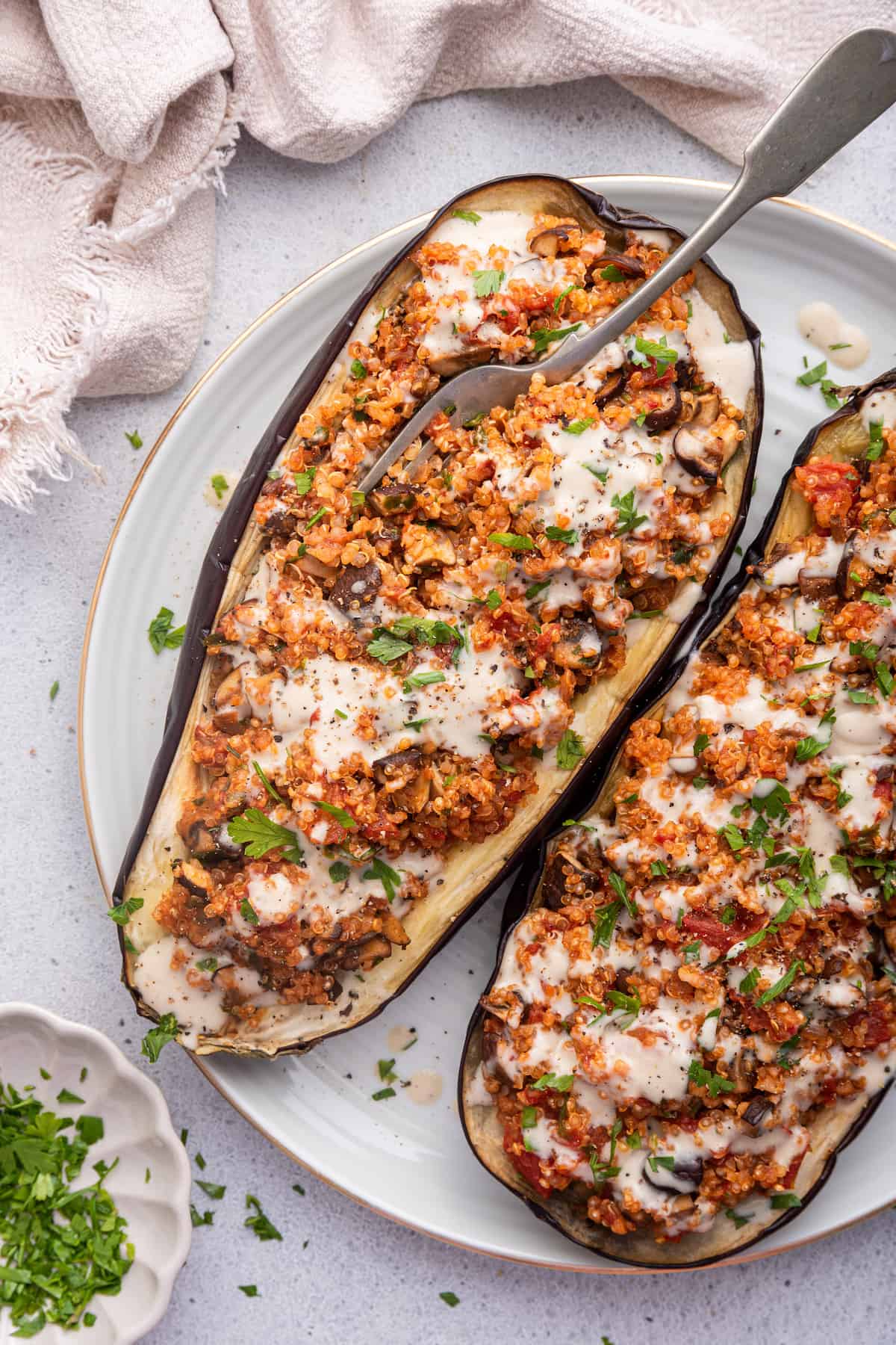 Overhead view of two stuffed eggplant halves on plate with fork