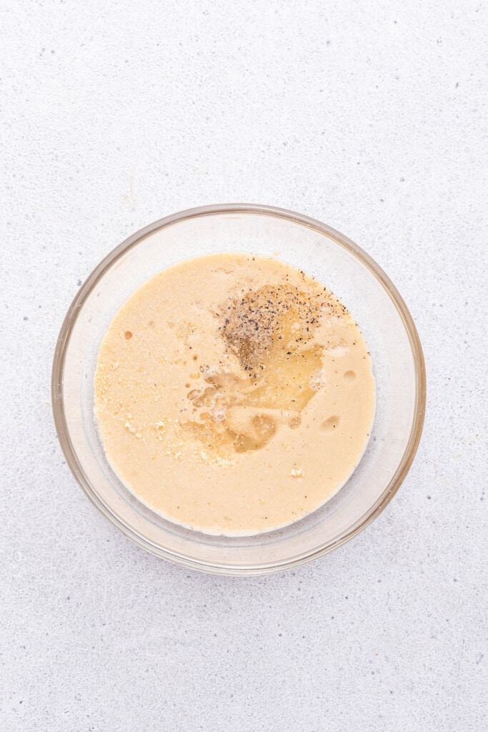 Overhead view of ingredients for tahini sauce in glass bowl