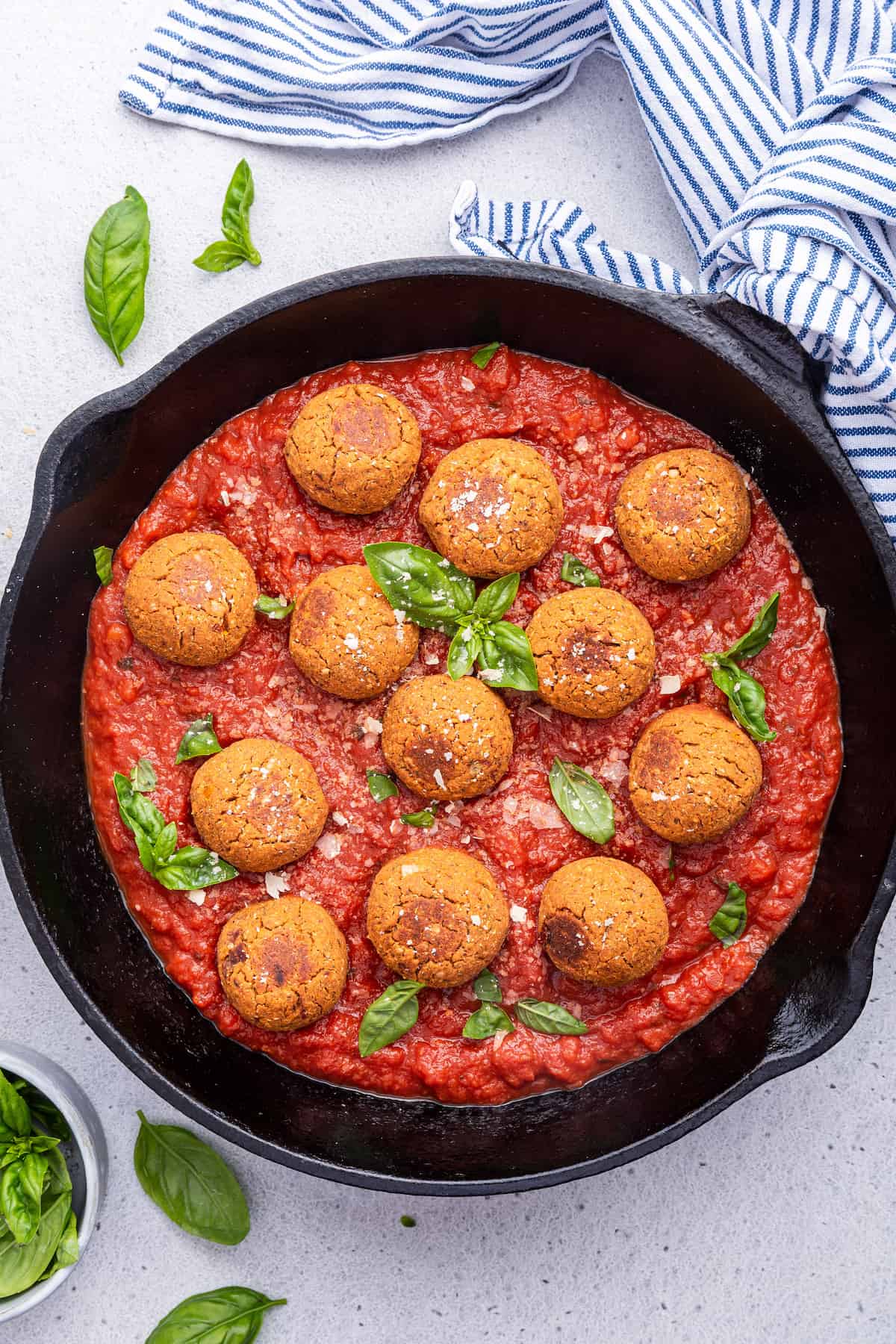 Overhead view of vegan meatballs in cast iron skillet of pasta sauce
