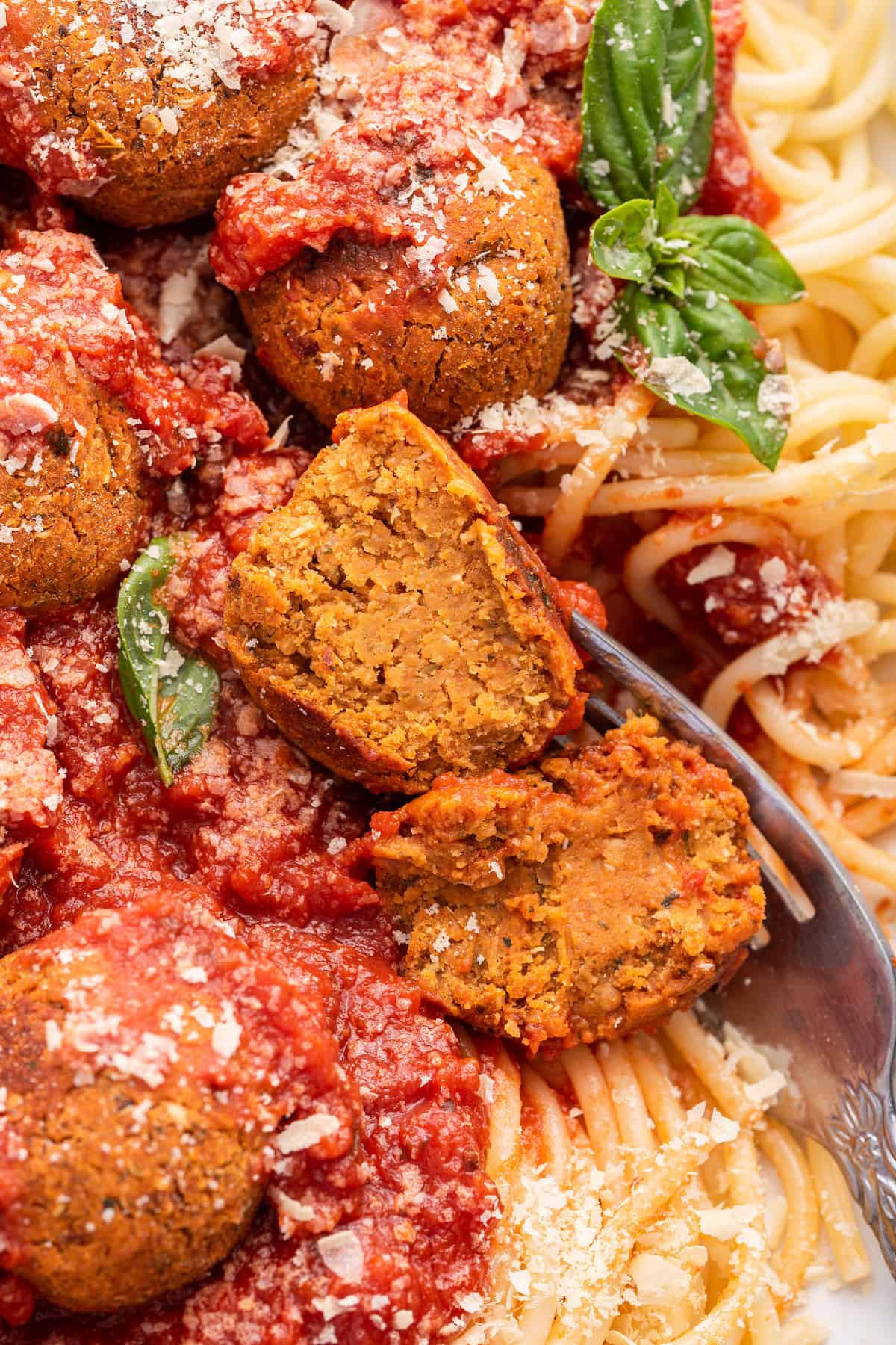Closeup of vegan spaghetti and meatballs with one meatball cut open to show texture
