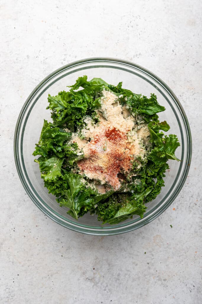 Overhead view of raw kale and seasonings in bowl