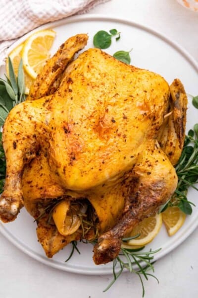 Instant Pot whole chicken on platter with sprigs of fresh herbs and lemons
