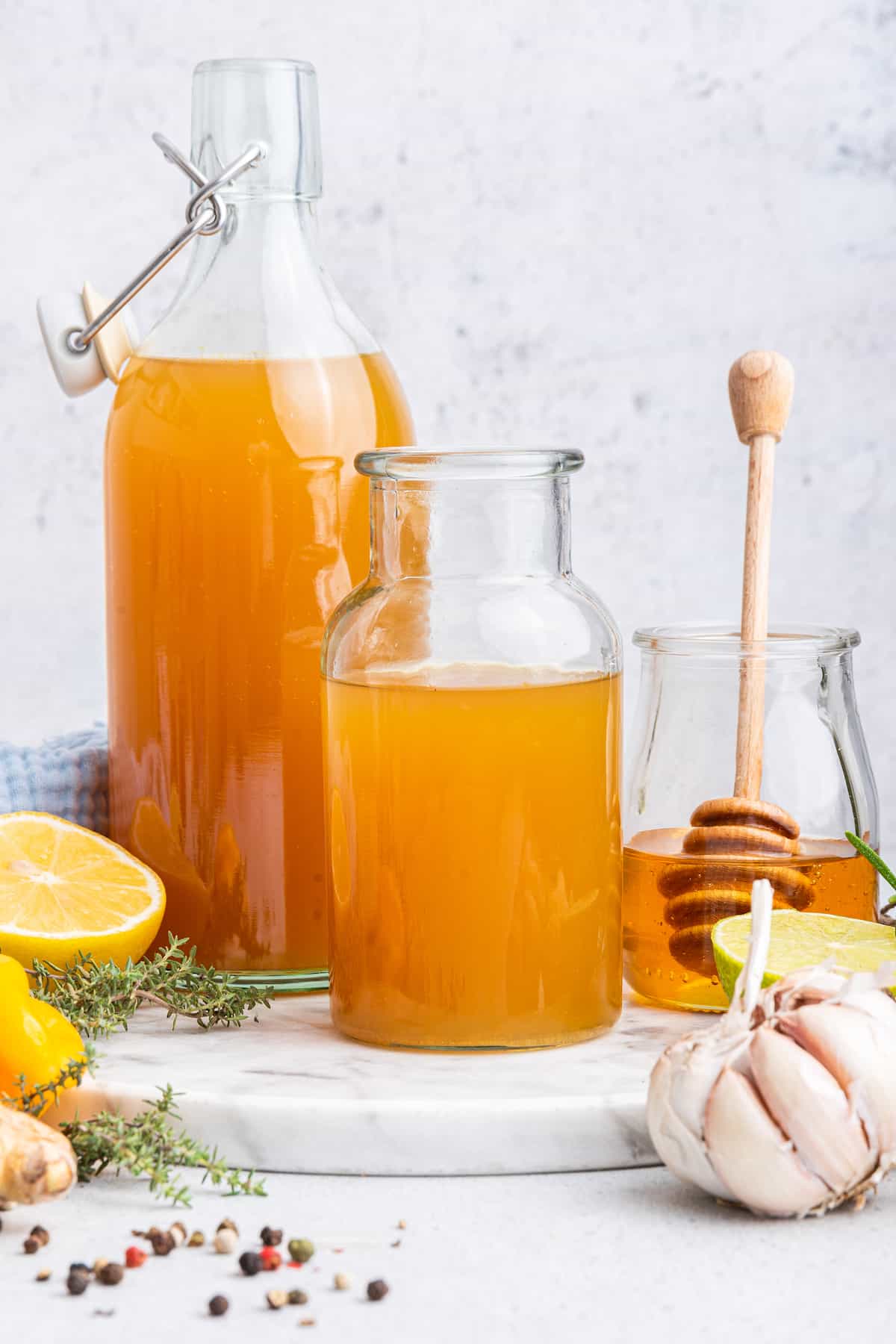 Two bottles of fire cider set next to jar of honey with dipper