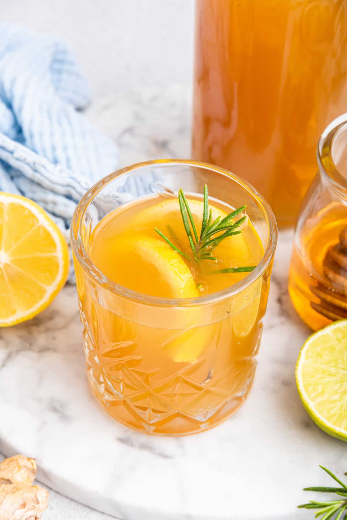 Top down view of fire cider in glass with lemon wedges and rosemary sprig