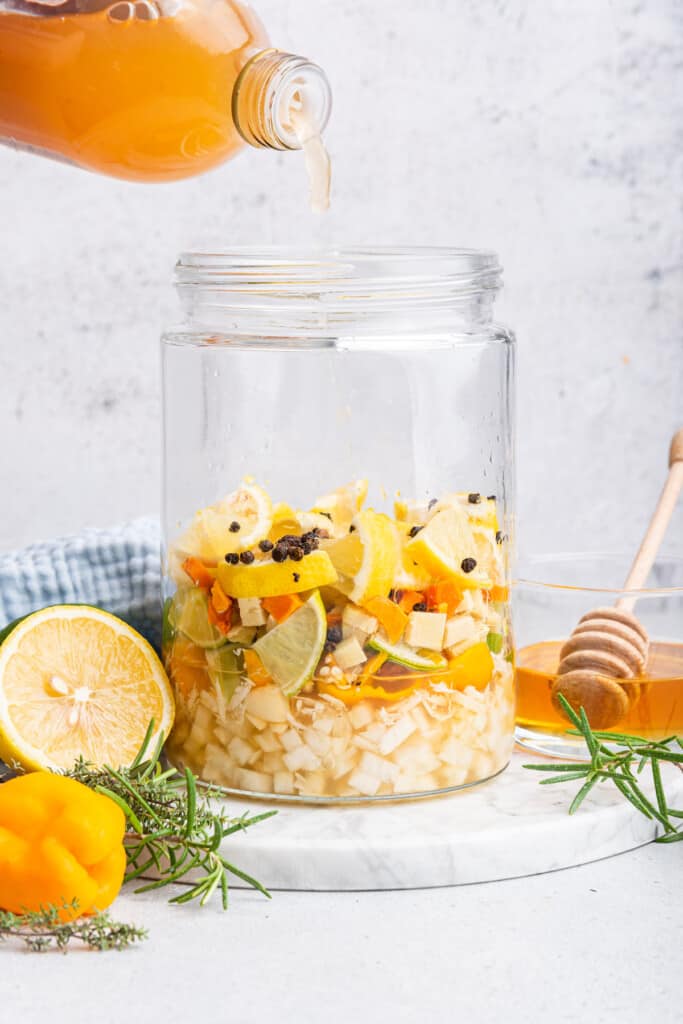 Pouring vinegar over ingredients for fire cider