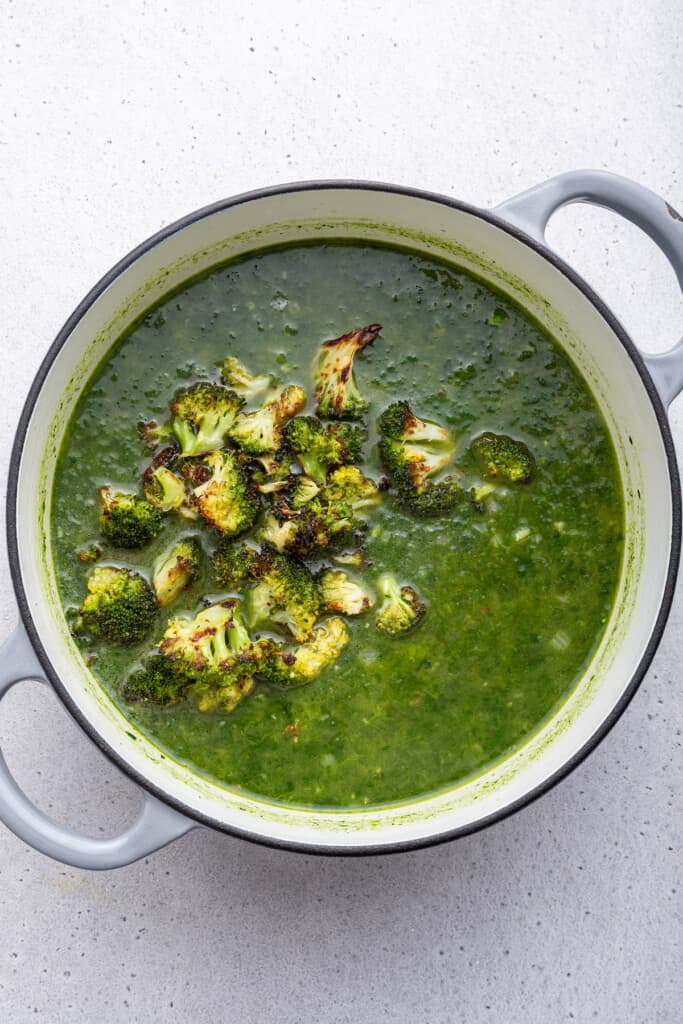 Overhead view of broccoli added to pot of soup