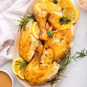 Overhead view of Instant Pot whole chicken on platter with lemon slices and rosemary sprigs