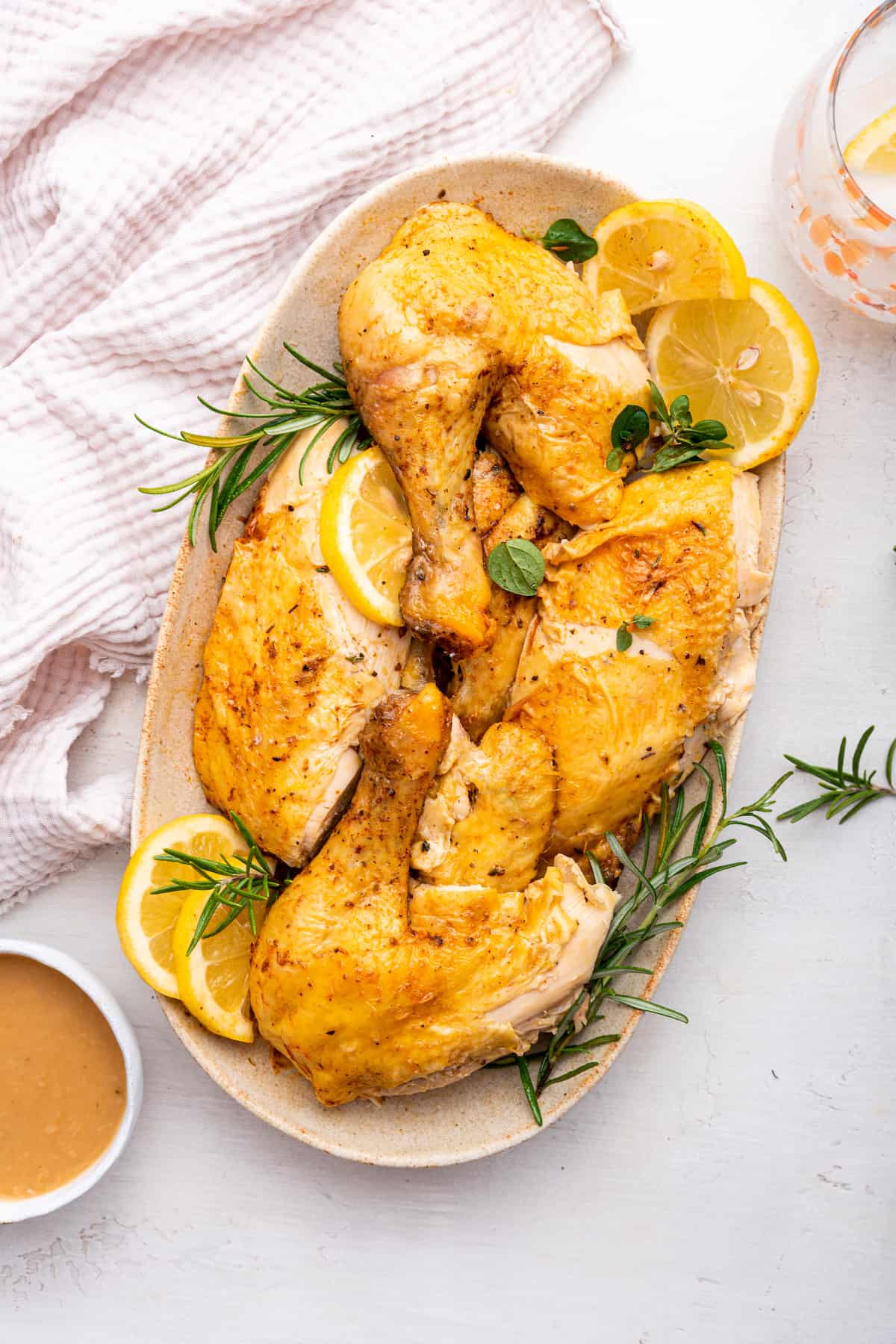 Overhead view of Instant Pot whole chicken on platter with lemon slices and rosemary sprigs