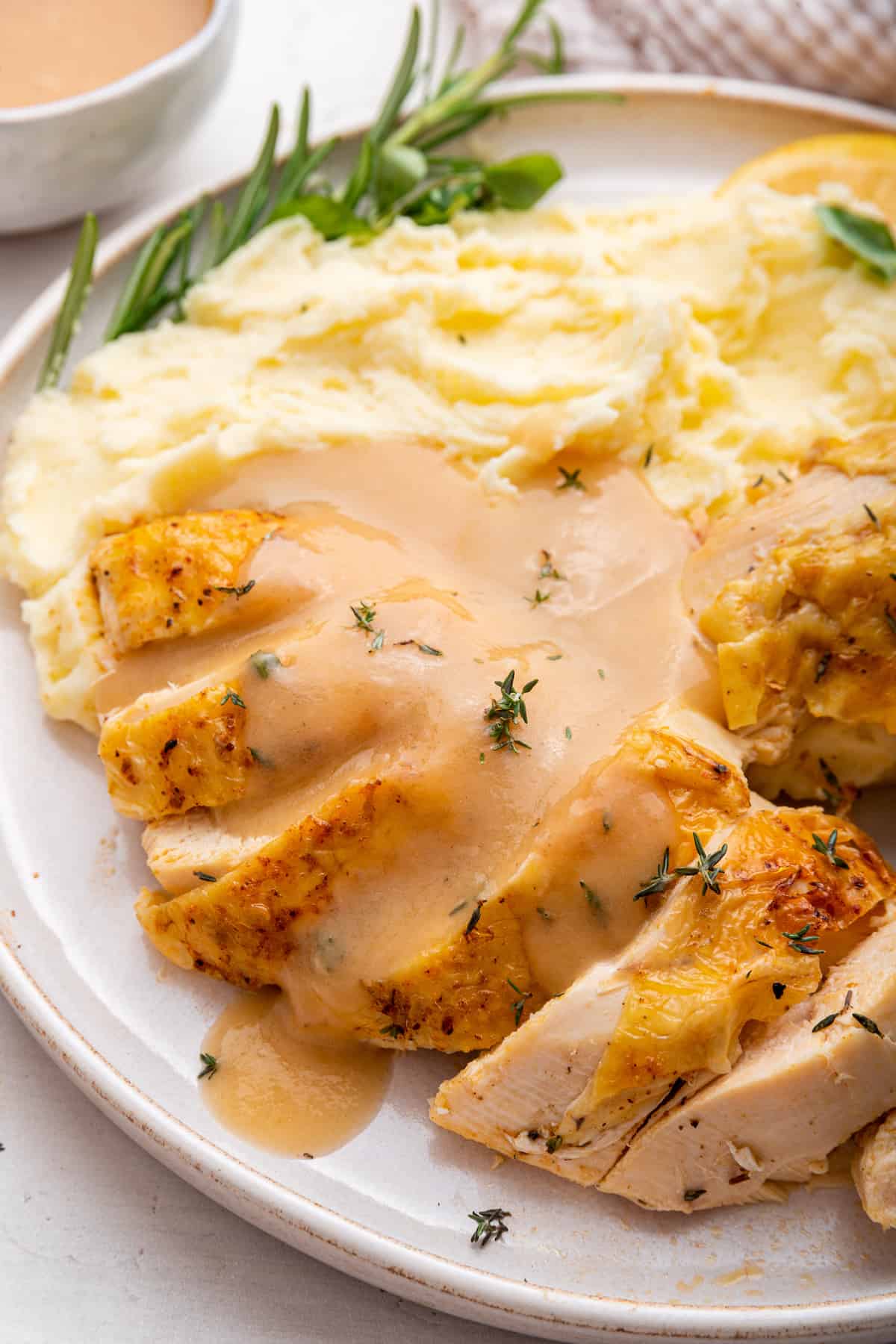 Sliced Instant Pot whole chicken on plate with mashed potatoes and gravy