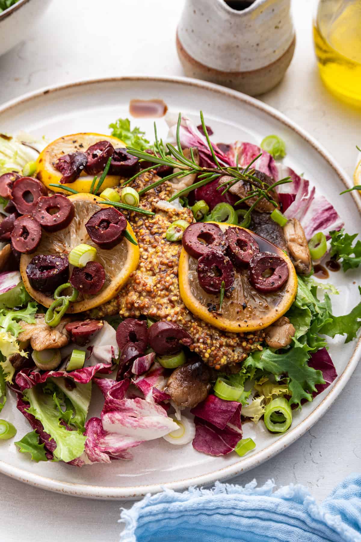Baked halibut with lemons, olives, and rosemary with bed of greens