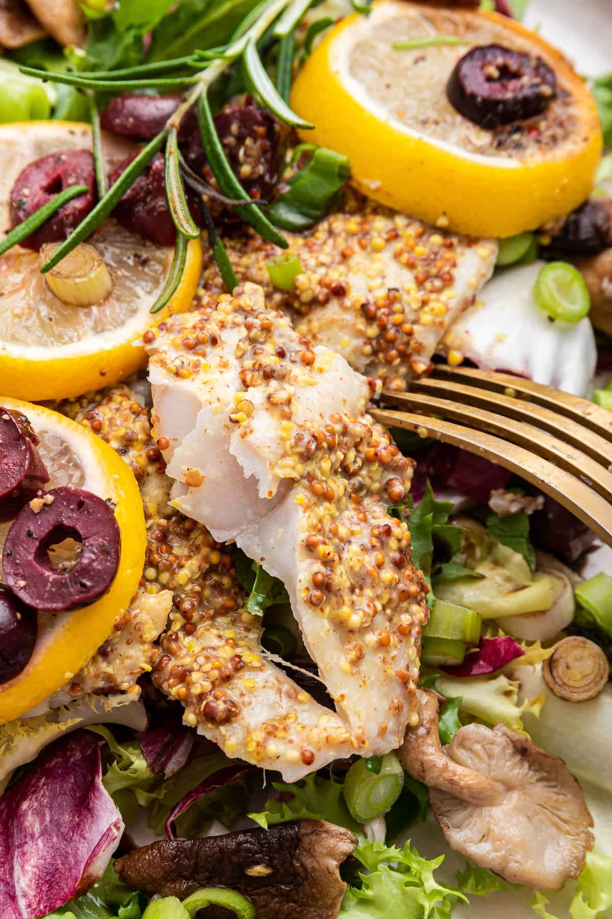 Fork piercing into baked halibut in salad