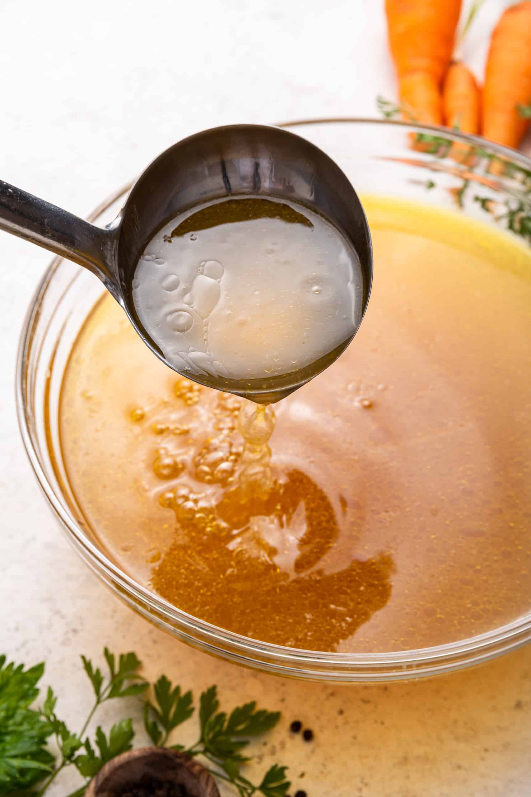 Ladling Instant Pot chicken bone broth into glass bowl