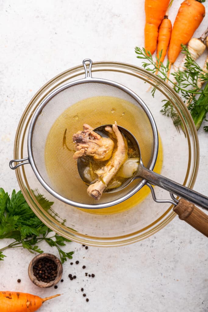 Straining Instant Pot chicken bone broth into bowl