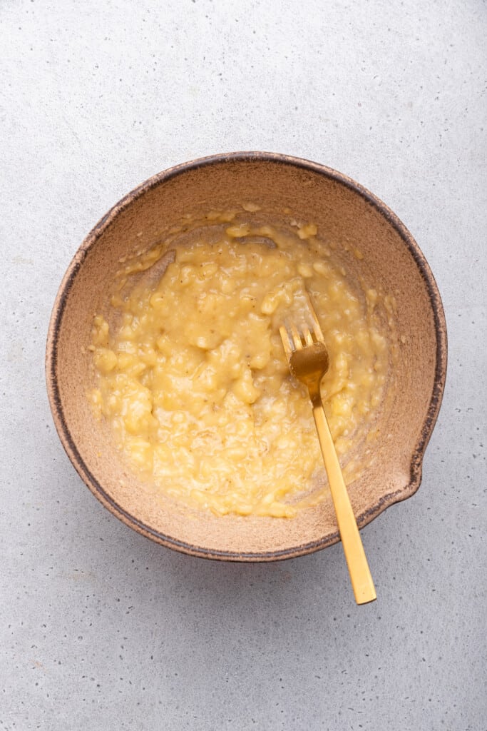 Overhead view of mashed banana in bowl with fork
