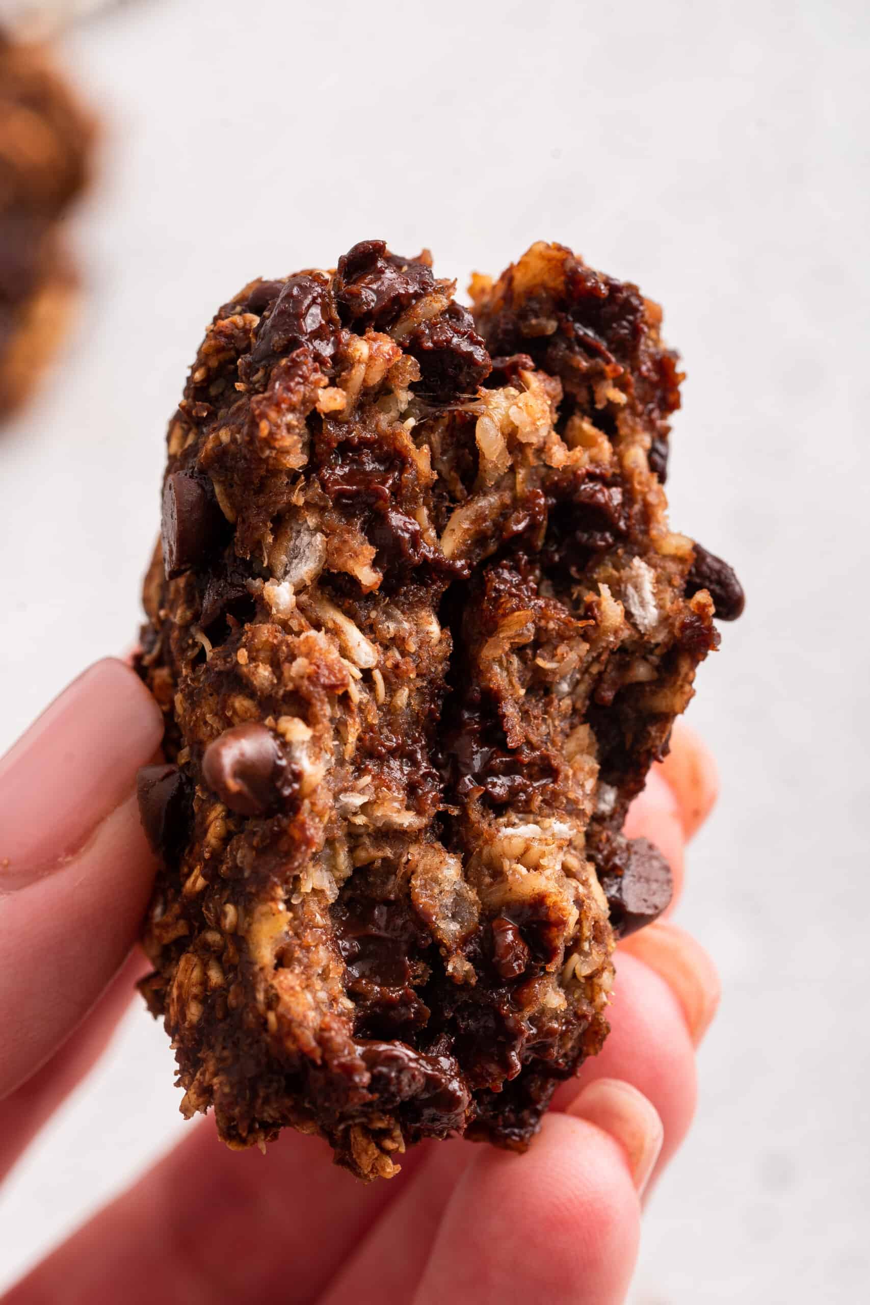 Hand holding banana oatmeal cookie broken in half to show texture