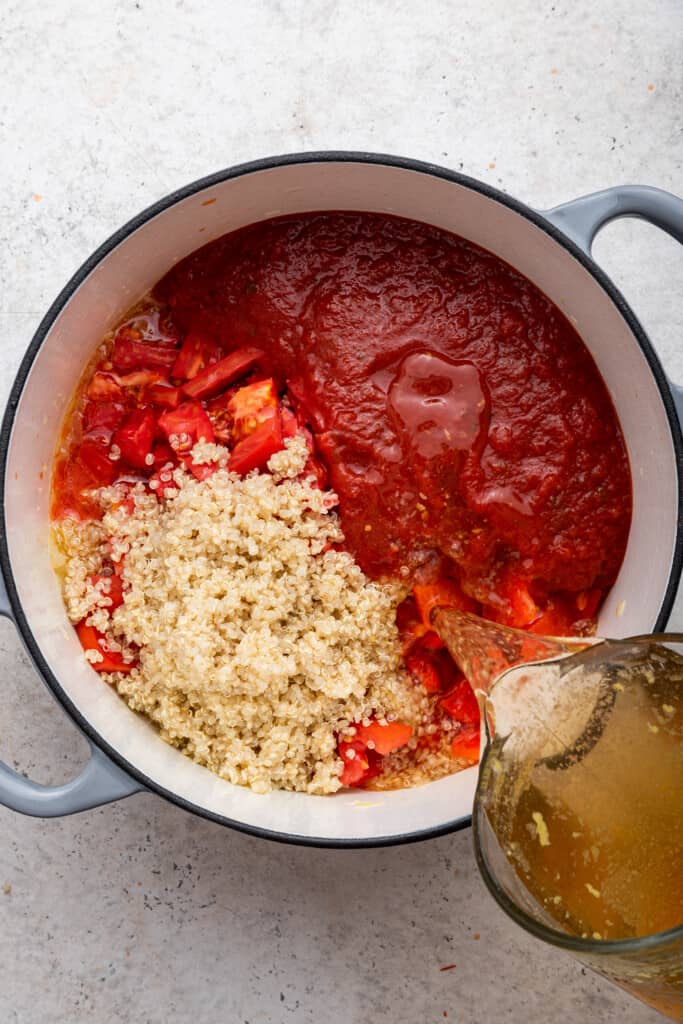 Pouring broth into pot of roasted red pepper soup