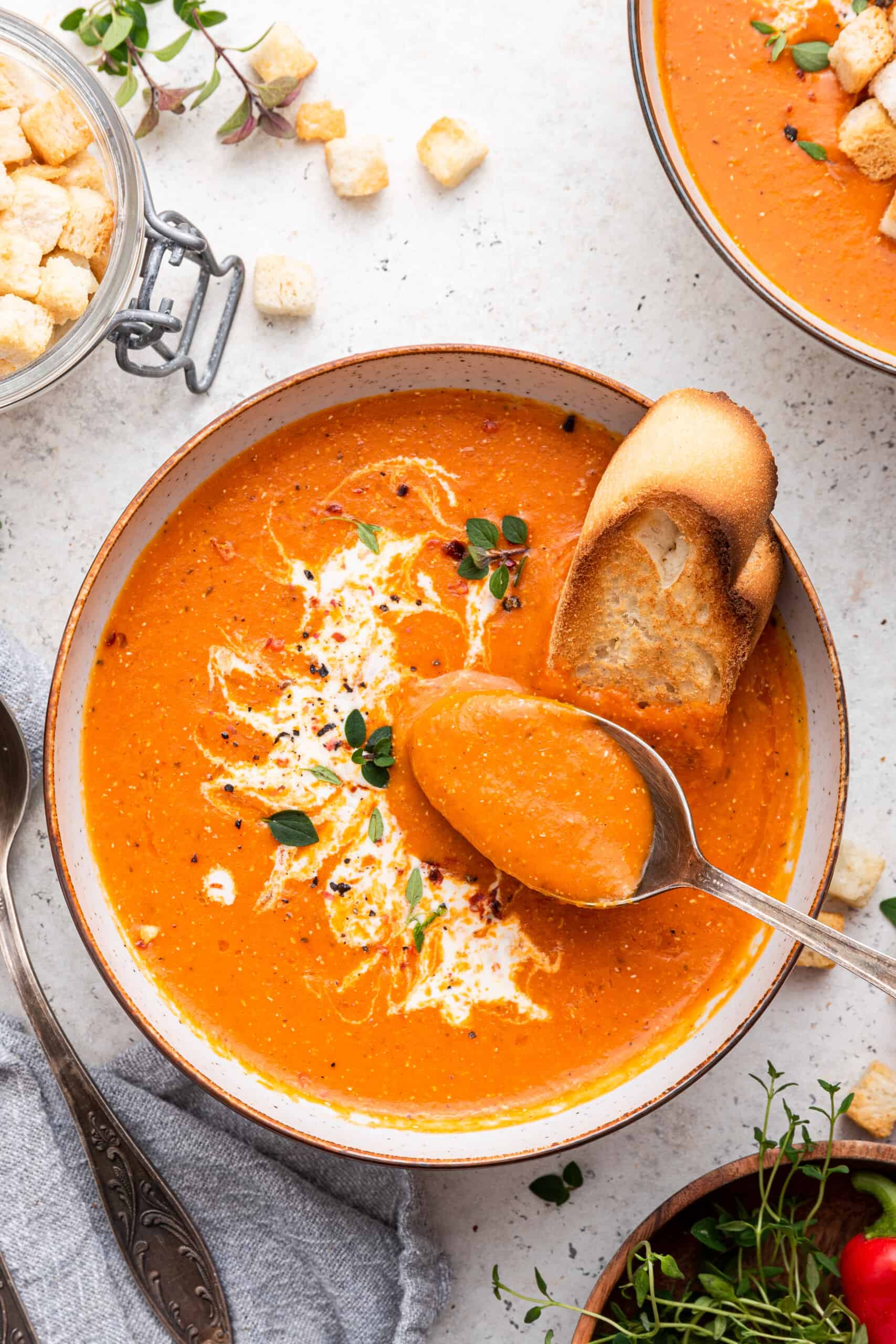 Bowl of roasted red pepper soup with spoon and toasted bread