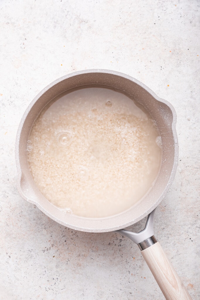 Overhead view of sushi rice in pot with water