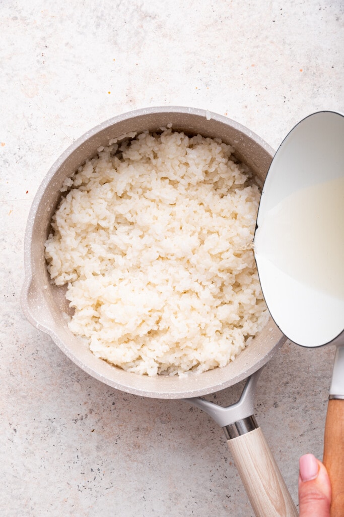 Overhead view of vinegar mixture being poured into rice