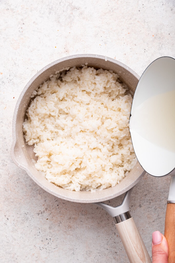 Overhead view of vinegar mixture being poured into rice