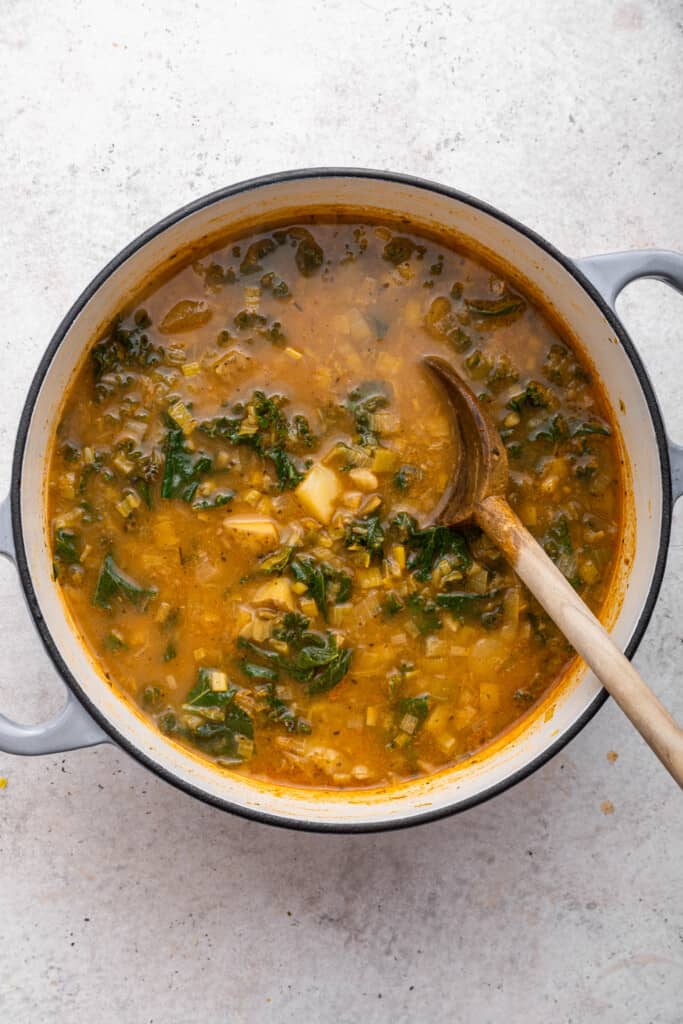Pot of vegan potato soup with wooden spoon
