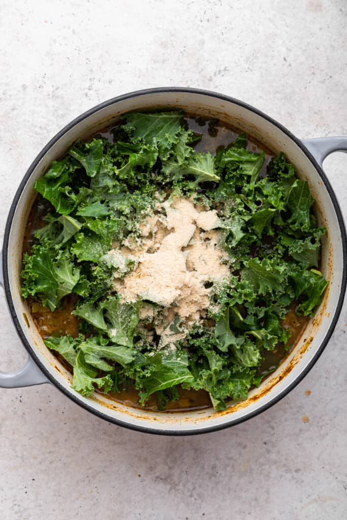 Kale and nutritional yeast added to pot of soup
