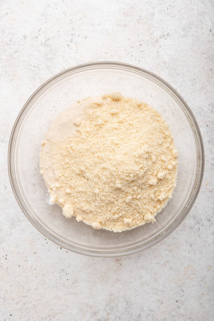 Overhead view of almond flour added to cottage cheese mixture in bowl