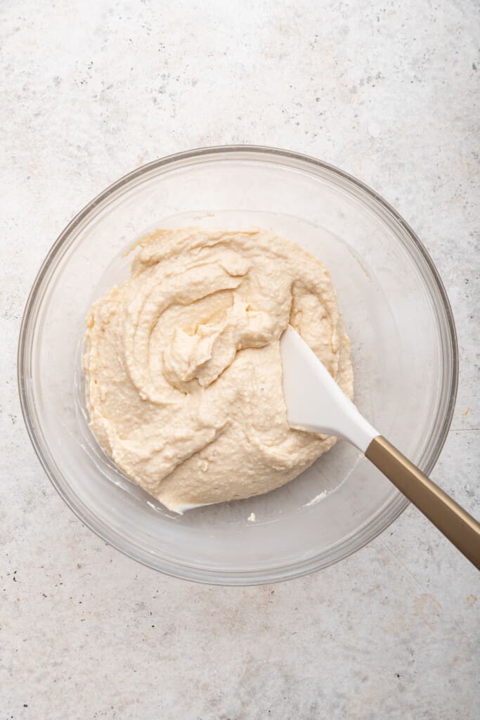 Overhead view of cottage cheese cookie dough in glass bowl with rubber spatula