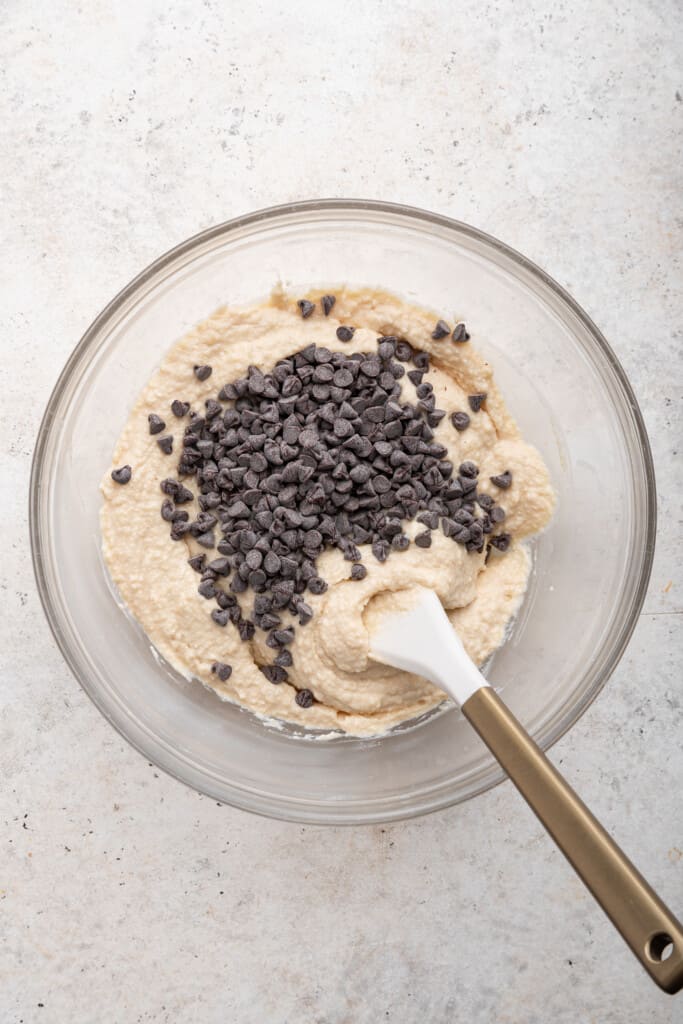 Overhead view of mini chocolate chips added to bowl of cottage cheese cookie dough