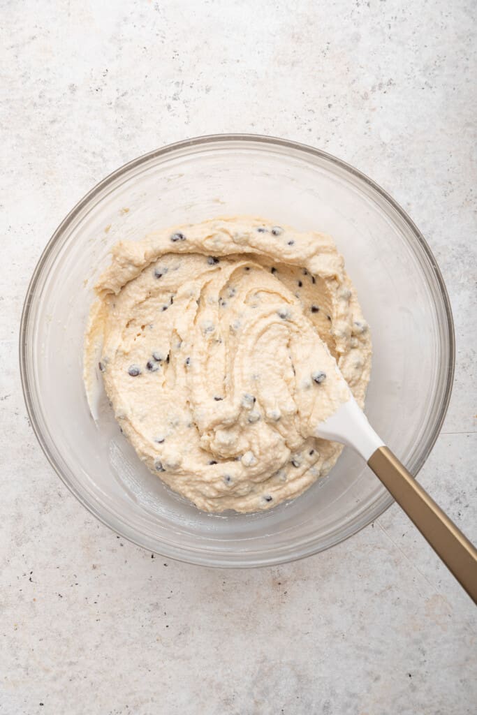Overhead view of spatula stirring cottage cheese cookie dough in glass bowl