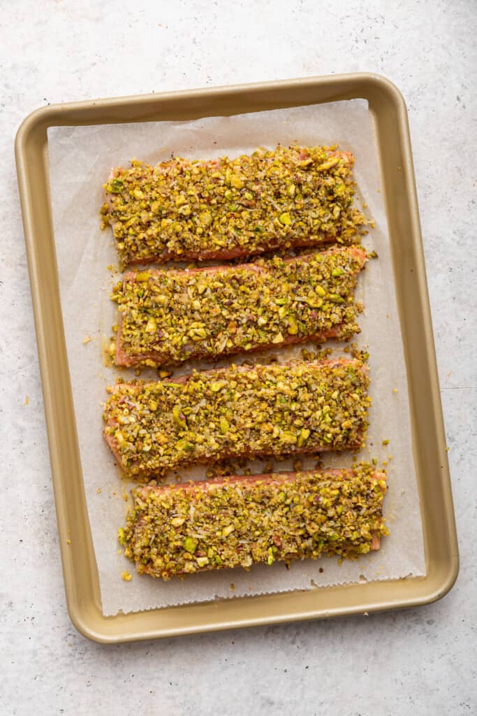 Overhead view of pistachio crusted salmon fillets on pan before baking