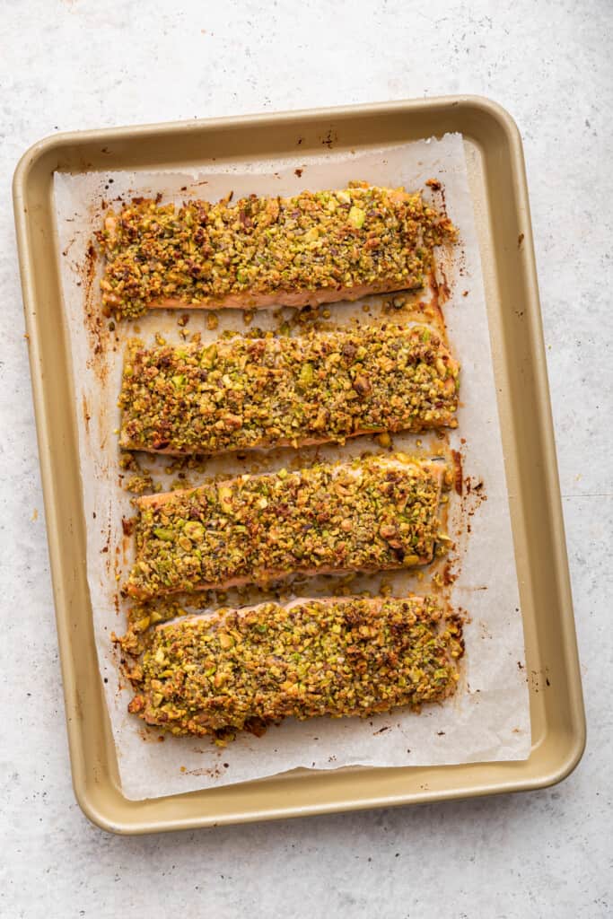 Overhead view of 4 pistachio crusted salmon fillets on sheet pan