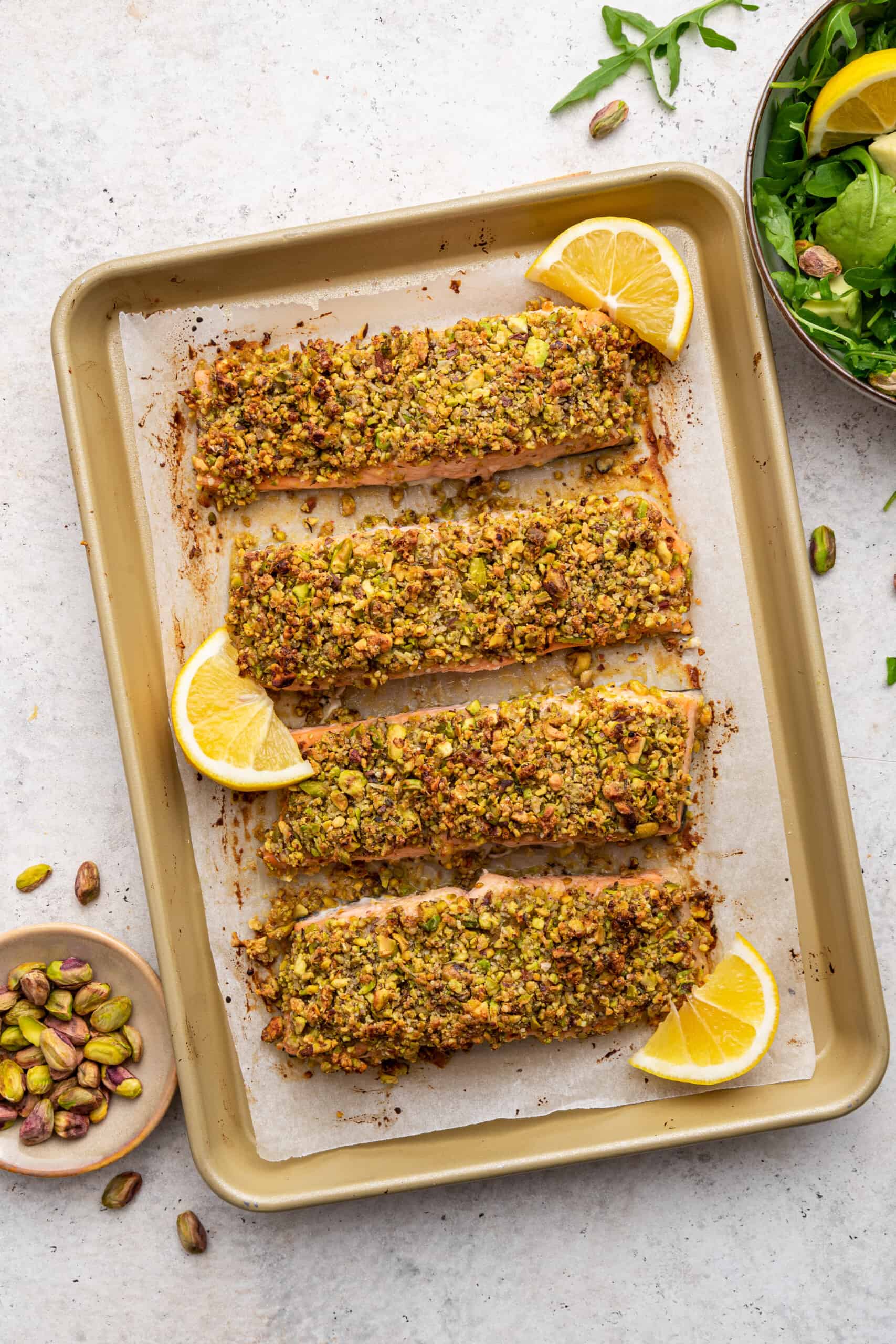 Overhead view of 4 pistachio crusted salmon fillets on sheet pan