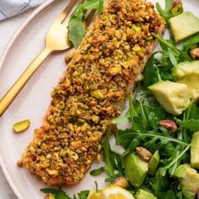 Pistachio crusted salmon on plate with salad and fork