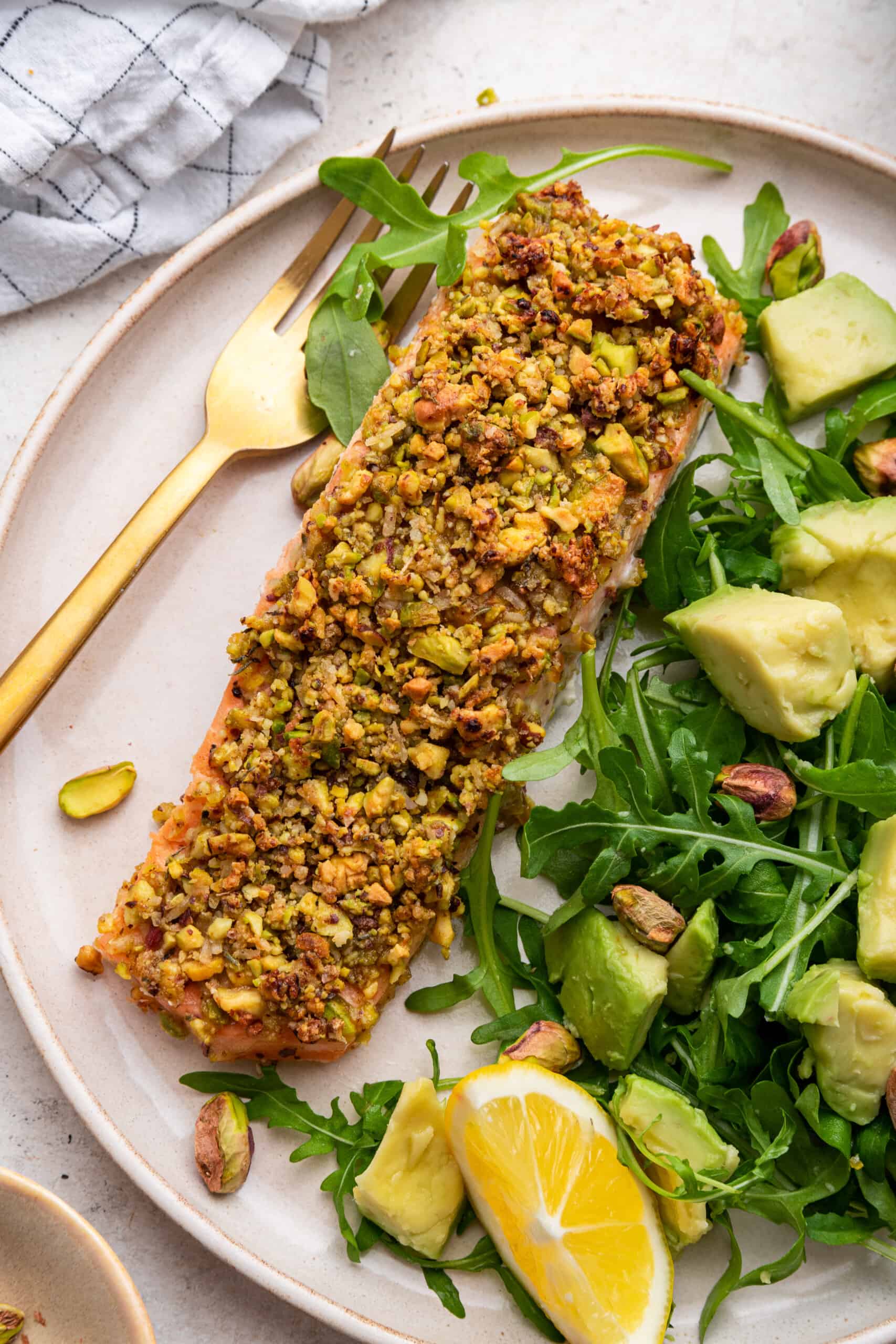 Pistachio crusted salmon on plate with salad and fork