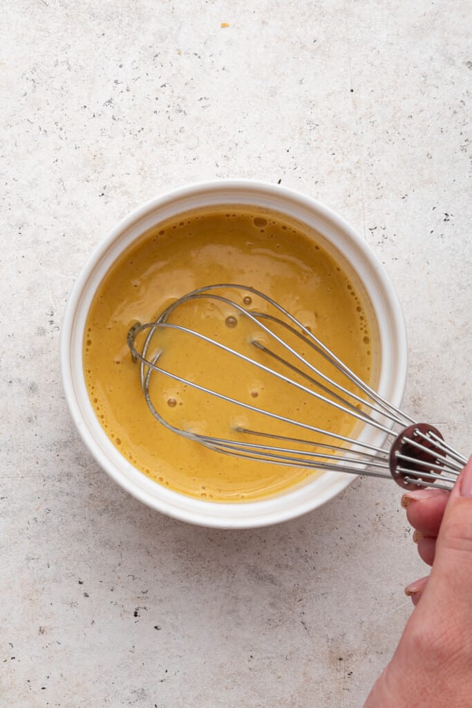 Overhead view of honey dijon glaze in bowl with whisk