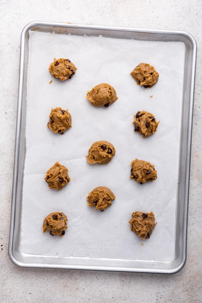 Overhead view of tahini chocolate chip cookie dough on parchment lined baking sheet